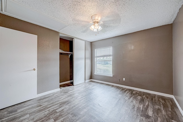 unfurnished bedroom featuring ceiling fan, a closet, wood-type flooring, and a textured ceiling