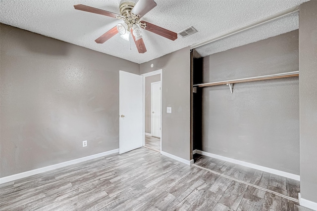 unfurnished bedroom with ceiling fan, a closet, light hardwood / wood-style floors, and a textured ceiling