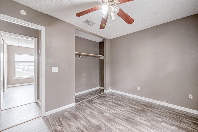 unfurnished bedroom with hardwood / wood-style flooring, ceiling fan, a textured ceiling, and a closet