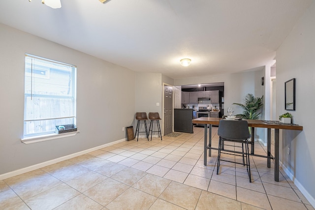 interior space featuring light tile patterned flooring, kitchen peninsula, stainless steel electric stove, and a breakfast bar area