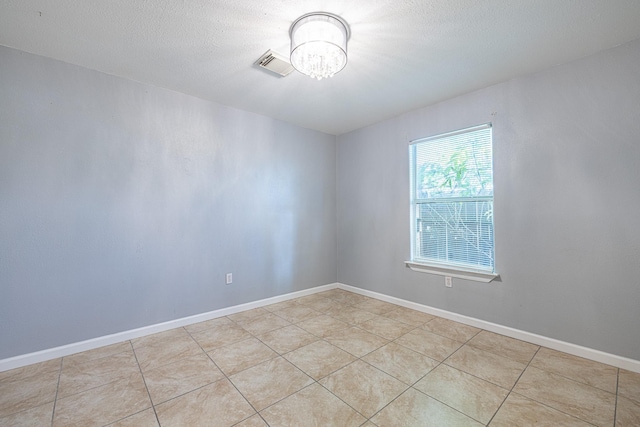 spare room featuring a textured ceiling, a notable chandelier, and light tile patterned flooring