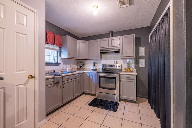 kitchen with gray cabinetry, tasteful backsplash, a textured ceiling, stainless steel electric stove, and light tile patterned floors