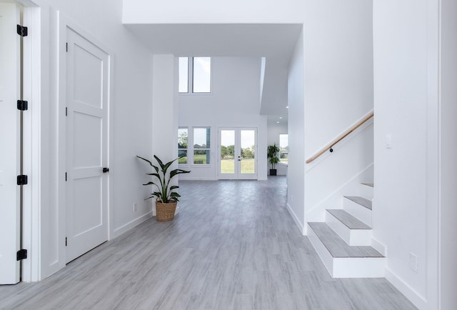 entryway featuring french doors, light hardwood / wood-style flooring, and a high ceiling