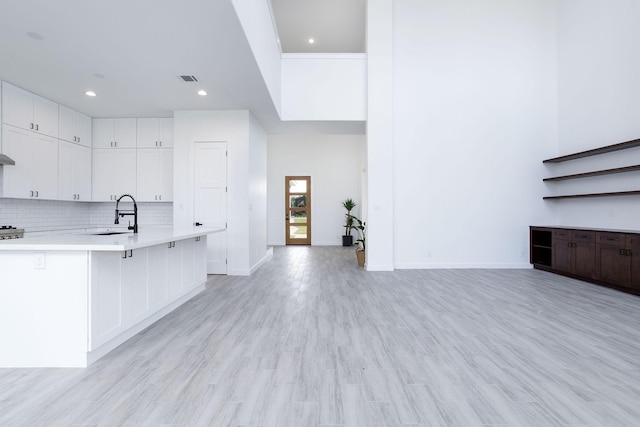 kitchen featuring a kitchen bar, light hardwood / wood-style flooring, white cabinetry, and sink