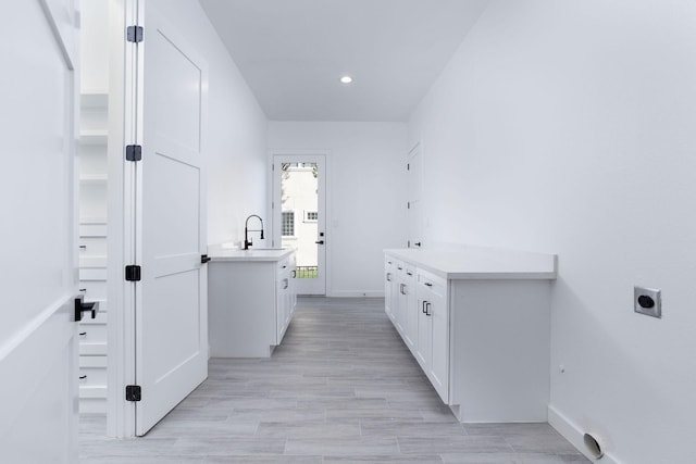 laundry room featuring hookup for an electric dryer, light wood-type flooring, cabinets, and sink