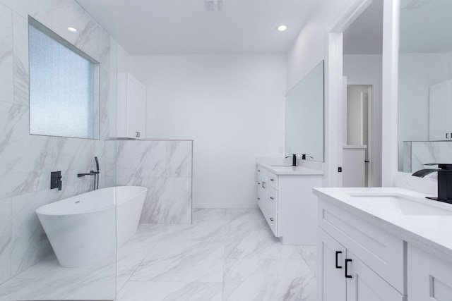 bathroom featuring vanity, a bath, and tile walls