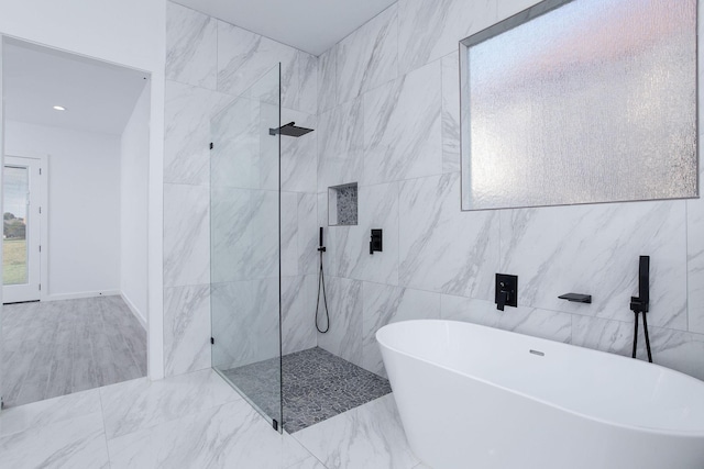 bathroom with separate shower and tub and tile walls