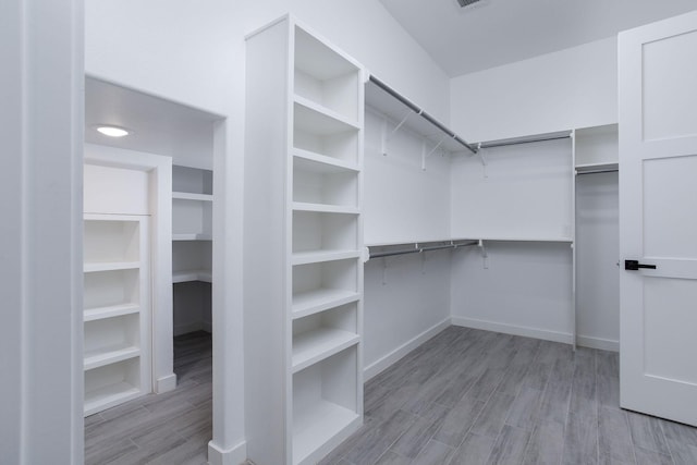 walk in closet with light hardwood / wood-style flooring