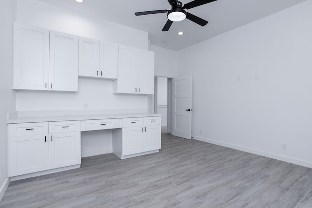 kitchen with white cabinets, ceiling fan, light wood-type flooring, and built in desk