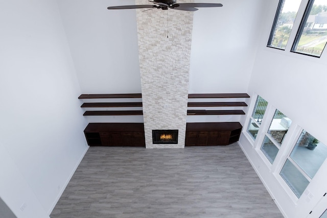 staircase featuring hardwood / wood-style floors, ceiling fan, a fireplace, and a high ceiling