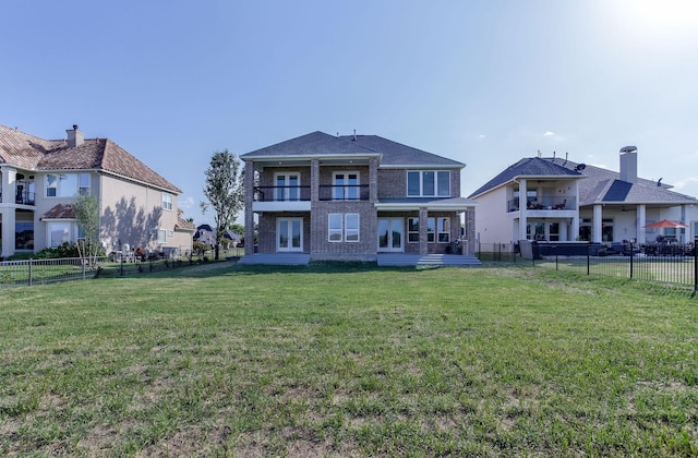 back of property featuring a balcony and a yard