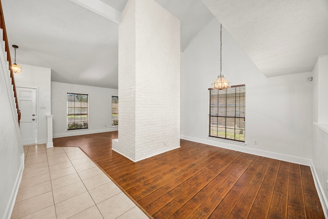 interior space featuring a textured ceiling, lofted ceiling with beams, light hardwood / wood-style floors, and a notable chandelier