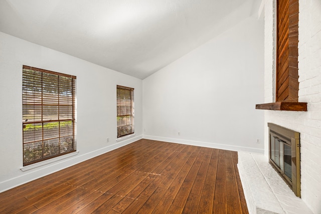 unfurnished living room with a brick fireplace, vaulted ceiling, and light wood-type flooring