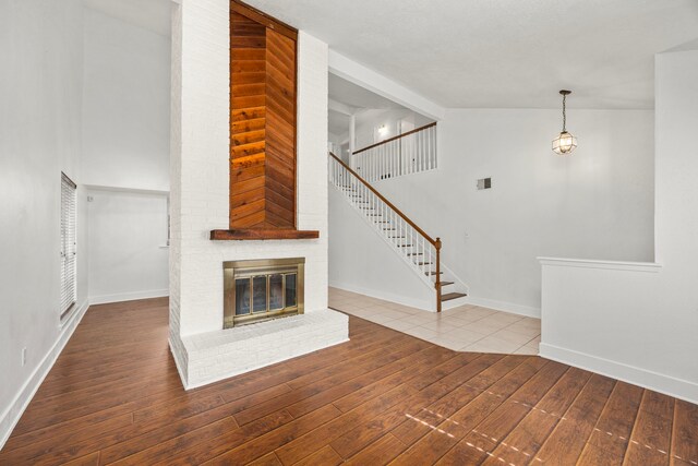 unfurnished living room with hardwood / wood-style flooring, lofted ceiling, and a fireplace