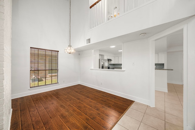 interior space with light hardwood / wood-style flooring, a towering ceiling, and a chandelier