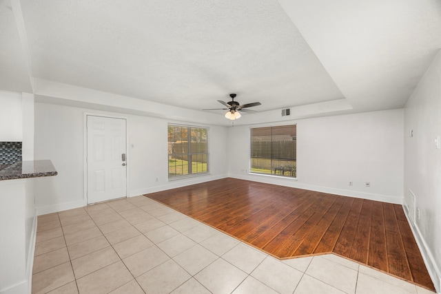 empty room with ceiling fan, light hardwood / wood-style floors, and a textured ceiling