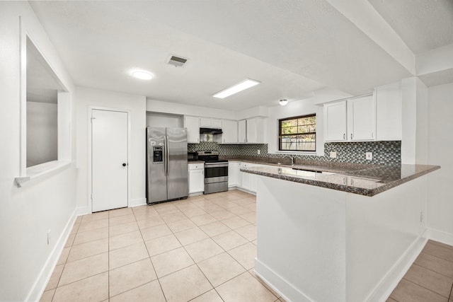 kitchen featuring kitchen peninsula, tasteful backsplash, stainless steel appliances, light tile patterned floors, and white cabinetry