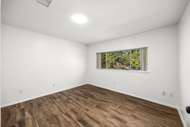 spare room with dark hardwood / wood-style flooring and a textured ceiling