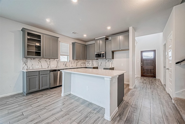 kitchen featuring backsplash, a kitchen island, light wood-type flooring, and appliances with stainless steel finishes