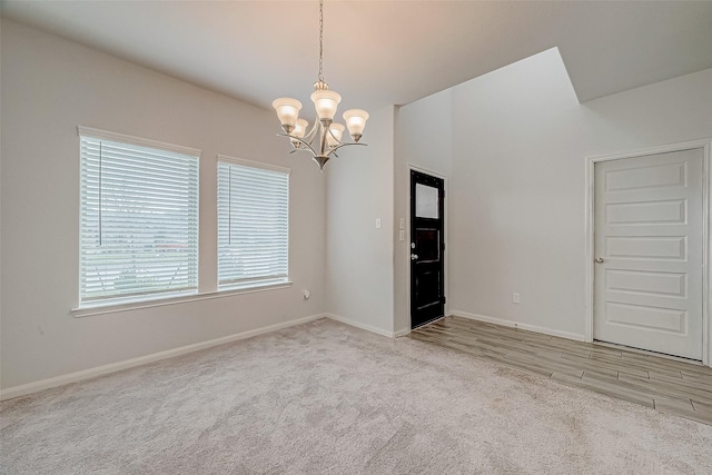 spare room with light carpet and a notable chandelier