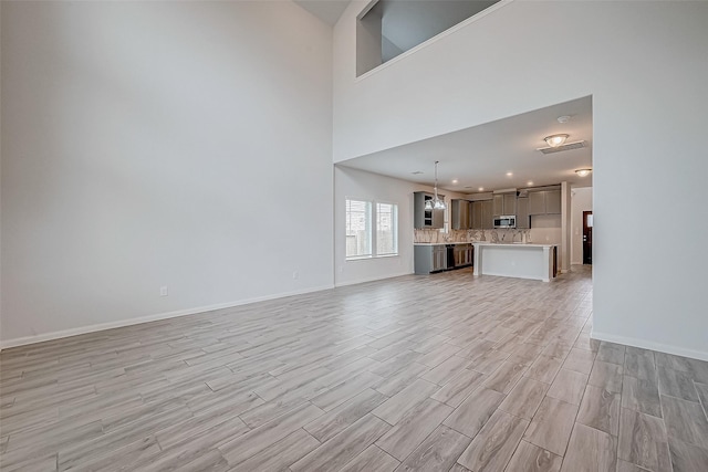 unfurnished living room with a towering ceiling and light hardwood / wood-style floors