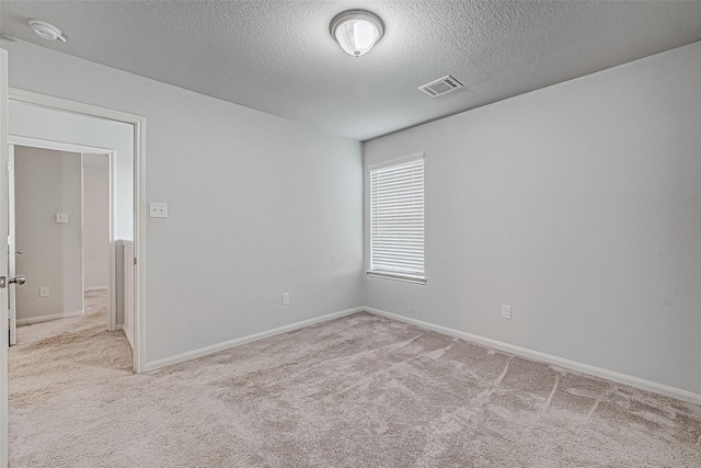 carpeted spare room with a textured ceiling