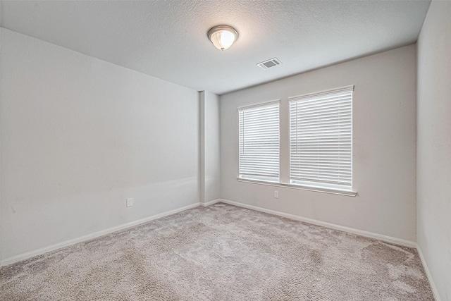 carpeted empty room featuring a textured ceiling