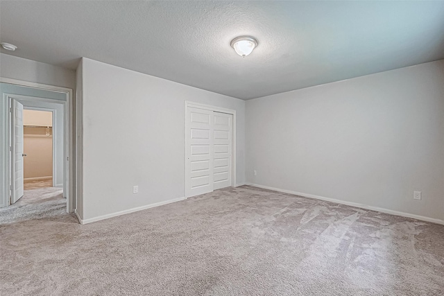 unfurnished bedroom with a textured ceiling, light colored carpet, and a closet