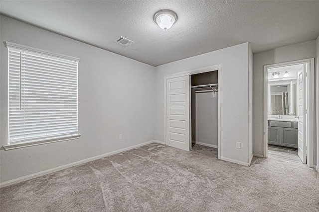 unfurnished bedroom featuring light carpet, a textured ceiling, and a closet