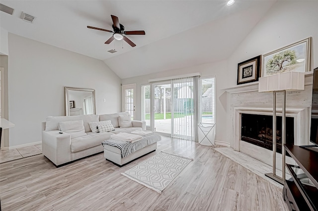 living room featuring ceiling fan, light wood-type flooring, lofted ceiling, and a high end fireplace