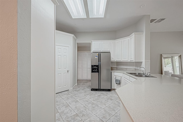 kitchen with white cabinetry, stainless steel fridge with ice dispenser, sink, and light tile patterned floors