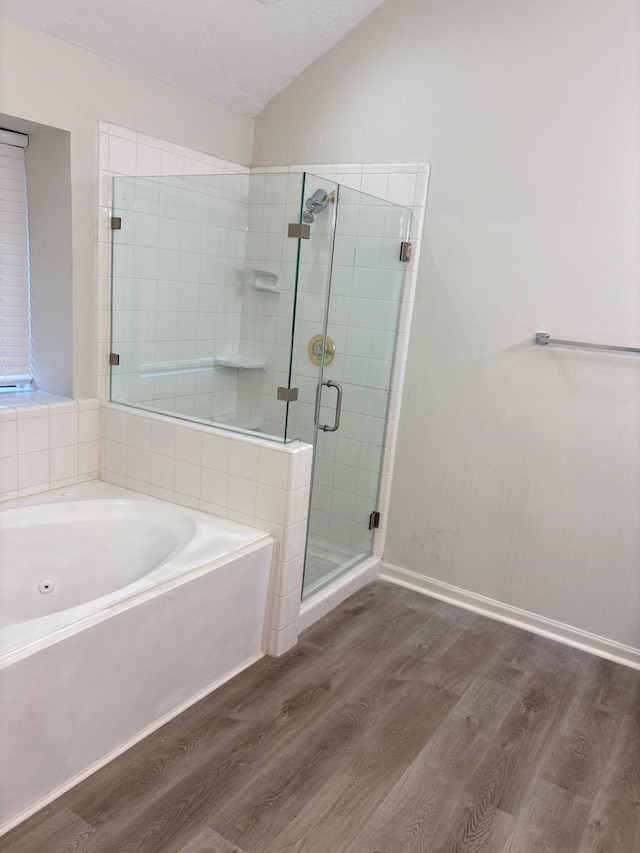 bathroom with plus walk in shower, a textured ceiling, and hardwood / wood-style flooring