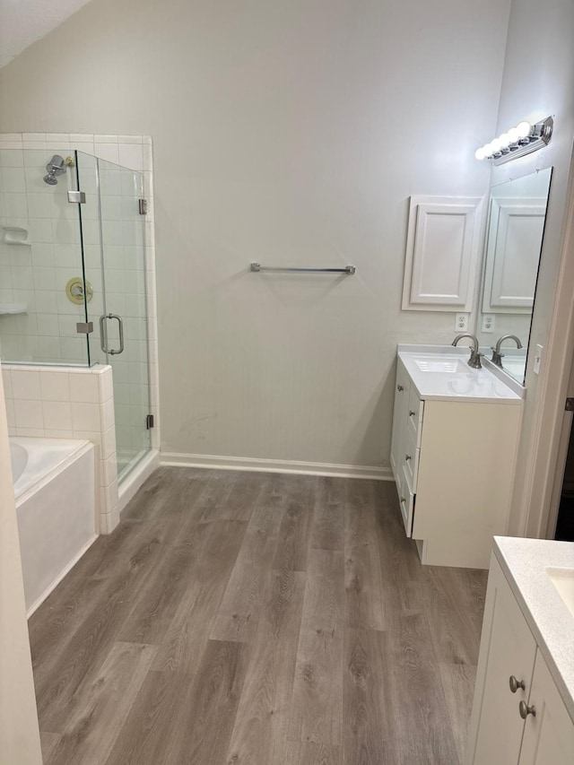 bathroom featuring hardwood / wood-style floors, vanity, vaulted ceiling, and independent shower and bath