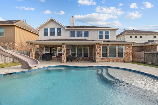 rear view of house featuring a patio area and a fenced in pool