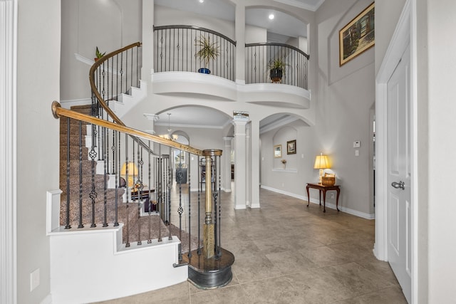 foyer featuring ornate columns, crown molding, and a towering ceiling