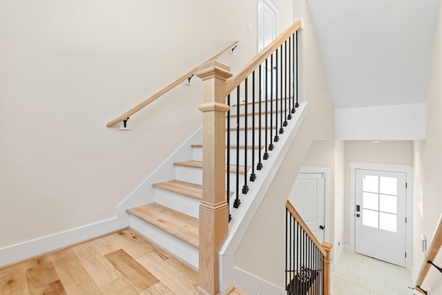 staircase featuring wood-type flooring and vaulted ceiling