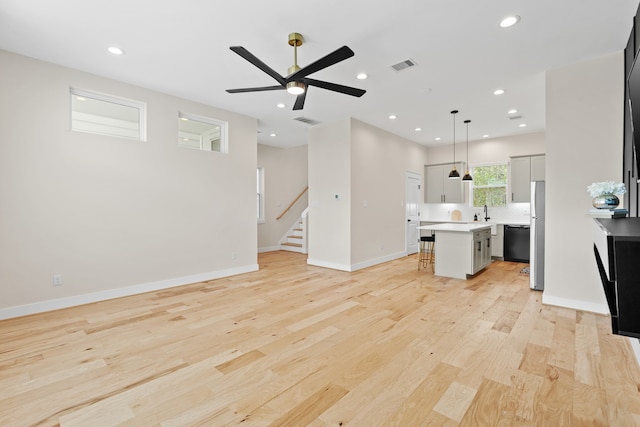 unfurnished living room with light hardwood / wood-style floors, ceiling fan, and sink