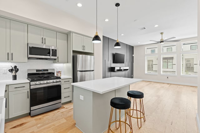 kitchen with ceiling fan, gray cabinets, decorative backsplash, light wood-type flooring, and stainless steel appliances