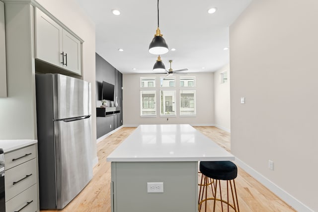 kitchen with a center island, ceiling fan, decorative light fixtures, light hardwood / wood-style floors, and stainless steel refrigerator