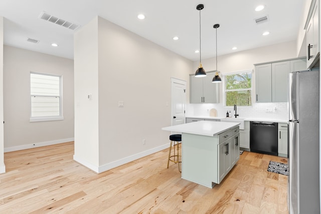 kitchen with a center island, backsplash, hanging light fixtures, stainless steel fridge, and black dishwasher