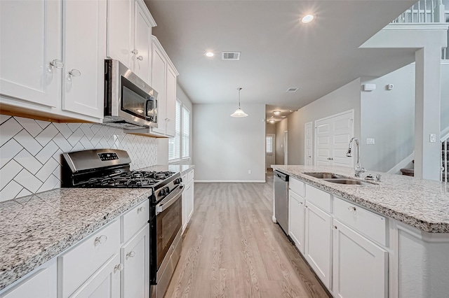 kitchen featuring sink, hanging light fixtures, light hardwood / wood-style flooring, white cabinets, and appliances with stainless steel finishes