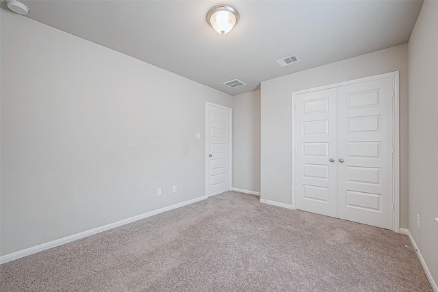 unfurnished bedroom featuring light carpet and a closet