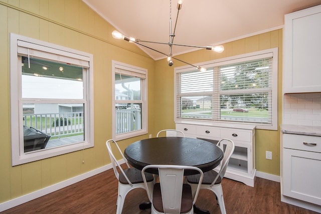 dining area with crown molding, dark wood-type flooring, vaulted ceiling, and an inviting chandelier