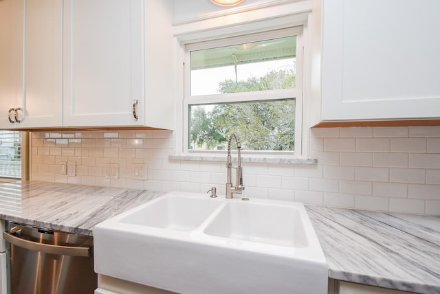 kitchen featuring light stone counters, sink, white cabinets, and stainless steel dishwasher