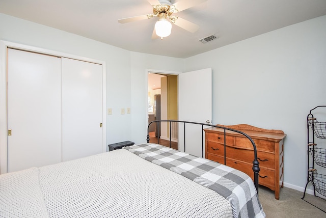 bedroom with ceiling fan, light colored carpet, stainless steel refrigerator, and a closet