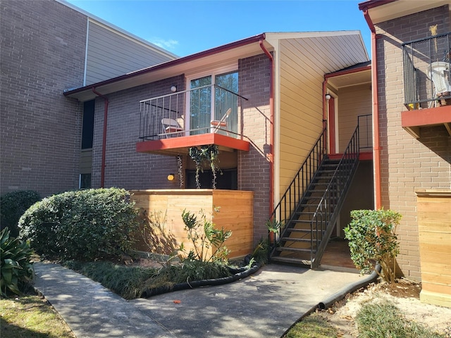 view of side of home featuring stairs, brick siding, and a balcony