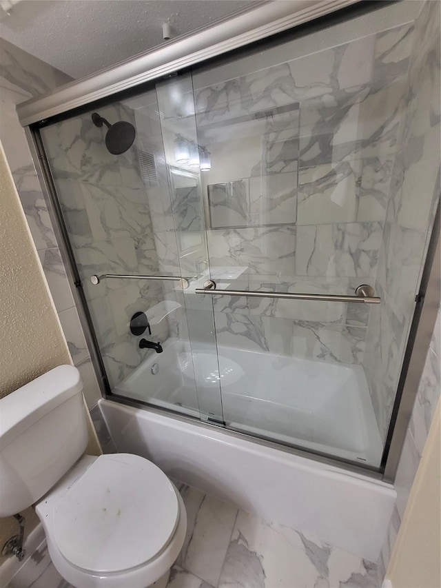 bathroom with bath / shower combo with glass door, a textured ceiling, and toilet