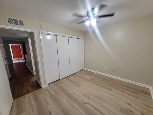 unfurnished bedroom featuring light wood-style flooring, a ceiling fan, visible vents, baseboards, and a closet