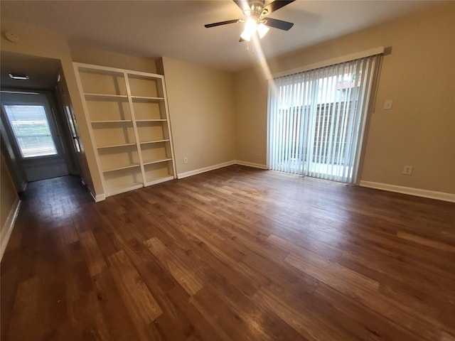 spare room with baseboards, a ceiling fan, and dark wood-type flooring