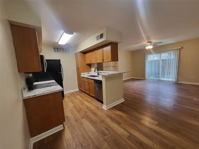 kitchen featuring brown cabinetry, open floor plan, visible vents, and stainless steel dishwasher